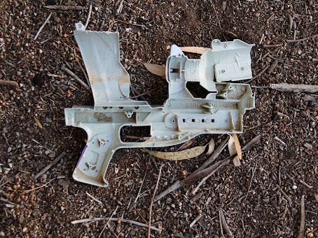 Broken gun plastic shell of gun on the earthy ground.